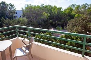 Balkon des Rosales Formentera Hotels mit Tisch, Stühlen und Blick auf eine bewaldete Landschaft