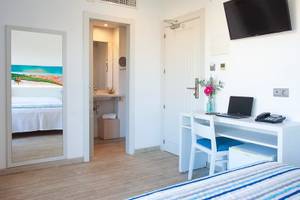 Innenansicht eines Hotelzimmers von Rosales Formentera, mit Schreibtisch, Laptop, Telefon und Fernseher.