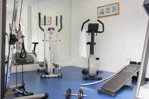 Fitnessraum im Hotel Voramar Formentera mit verschiedenen Trainingsgeräten und blauem Boden.