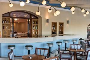 Innenansicht der Bar im Eliros Mare Hotel mit Tresen, Stühlen und Flaschen.