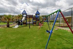 Spielplatz im Freien mit Rutsche und Schaukeln im Eliros Mare Hotel.