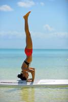 Eine Frau praktiziert Yoga auf einem Surfbrett im Wasser.