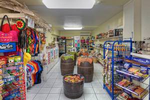 Innenansicht eines bunten Ladens im Coconut Court Beach Hotel mit Regalen voller Snacks, bunten T-Shirts und dekorativen Gegenständen.