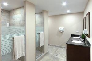Badezimmer im Coconut Court Beach Hotel mit Glasdusche und Waschbecken.