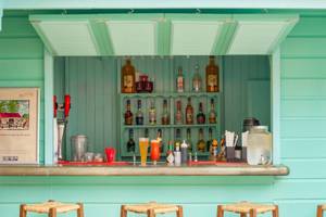 Cocktailbar im Sugar Bay Barbados mit grünen Wänden und einer Auswahl an Getränken.