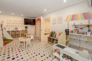 Ein buntes Kinderzimmer im Sugar Bay Barbados Hotel mit Tisch, Stühlen und einem Teppich mit bunten Punkten.