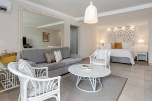 Modernes Zimmer im Sugar Bay Barbados Hotel mit grauem Sofa, weißem Tisch und großem Spiegel.