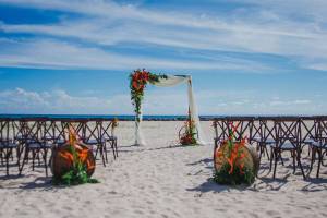 Hochzeitszeremonie auf dem Strand des Hilton Barbados mit Blumenbogen und Stühlen.