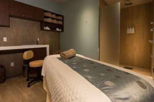 Massagebehandlungsraum im Hilton Barbados Hotel mit einem Bett, einem Stuhl und einer Dusche.