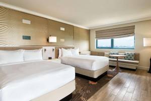 Doppelzimmer im Hilton Barbados mit zwei Betten, Couch, Tisch und Fenster mit Meerblick.