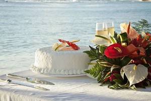 Hochzeitstorte am Strand des Mango Bay Hotels mit Meer im Hintergrund.