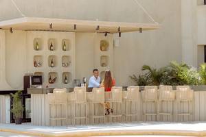 Ein Paar sitzt an der Bar des Sunrise Anjum Resorts, außen vor einer Wand mit Flaschen und Pflanzen.