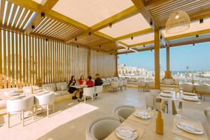 Innenbereich eines Restaurants im Sunrise Anjum Resort mit Gästen an Tischen und Blick auf das Meer.