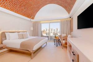 Schlafzimmer im Sunrise Anjum Resort mit einem Bett, Balkon, Fernseher und Möbeln.