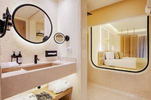 Badezimmer im Sunrise Anjum Resort mit modernem Design, großer Dusche und Blick auf das Bett.