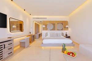Ein modernes Hotelzimmer im Sunrise Anjum Resort mit einem Bett, einem Tisch mit Früchten und einem Spiegel.