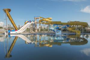 Wasserrutschen im Freizeitpark mit blauem Himmel und reflektiertem Wasser