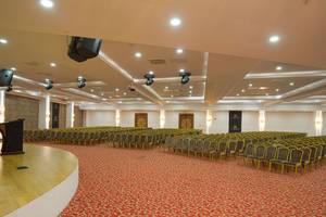 Ein Saal im Alan Xafira Deluxe Resort & Spa mit roten Teppich und Reihen von Stühlen.