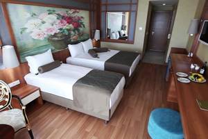 Ein Hotelzimmer mit zwei Betten, einem großen Gemälde, einer Kommode und einem Stuhl.