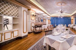 Innenansicht des Restaurants im Sensitive Premium Resort & Spa, mit gedeckten Tischen, blauen Vorhängen und Holzboden.