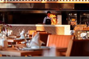 Koch in Steak-Restaurant beim Braten von Steaks mit Feuereffekt in der Küche.