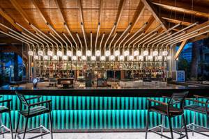 Bar im Kirman Leodikya Resort mit blauen Leuchtleisten und Metallstühlen.