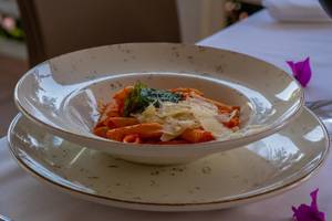 Ein Teller mit Penne Pasta und Blattspinat auf einem Tisch im Hotel Ducale Lara.