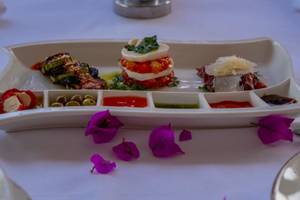 Eine Speiseplatte mit verschiedenen Toppings und Saucen, serviert im Ducale Lara Hotel.