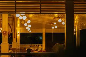 Veranda des Ducale Lara Hotels bei Nacht mit hängenden Lichtern und dunklem Hintergrund.