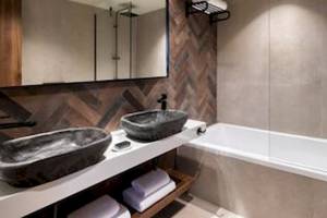 Ein Badezimmer mit zwei Waschbecken, einer Badewanne und einer Dusche im Domes Aulus Zante Hotel.