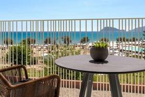 Ein Balkon mit Tisch und Stuhl bietet Aussicht auf das Meer und eine Bergkette.