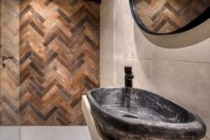 Badezimmer mit braunem Holz-Herzmuster an der Wand und einer schwarzen Marmor-Waschbecken.