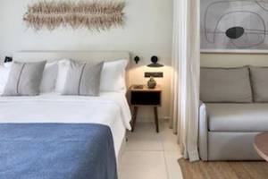 Hotelzimmer im Domes Aulus Zante mit einem Bett, einem Nachttisch und einem Sofa.