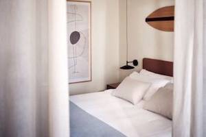 Schlafzimmer im Domes Aulus Zante Hotel mit Bett, Kissen und Wanddekoration.
