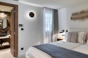 Schlafzimmer im Domes Aulus Zante Hotel mit Doppelbett, weißen Wänden und Deckenleuchten.