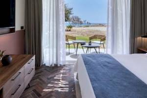 Innenansicht eines Hotelzimmers im Domes Aulus Zante mit Blick auf den Strand und das Meer.