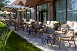 Terrasse des Domes Aulus Zante Hotels mit Tischen, Stühlen und Sonnenschirmen.