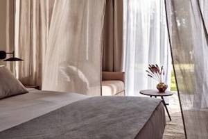 Schlafzimmer im Domes Aulus Zante Hotel mit Bett, Kopfteil, Kissen und Tisch mit Vase.