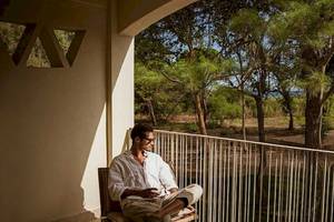Ein Mann sitzt auf einem Stuhl auf der Balkon im Domes Aulus Zante Hotel.