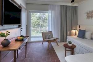 Innenansicht der Suite im Domes Aulus Zante Hotel mit Fernseher, Sofa, Tisch und Fenster.