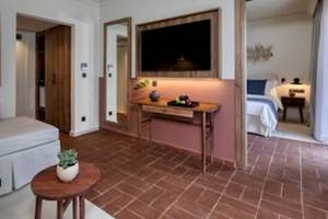 Suitenzimmer im Domes Aulus Zante mit Fernseher, Tisch, Sofa und Schlafzimmer.