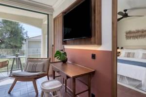 Ein modernes Hotelzimmer mit Balkon, Fernseher und bequemem Bett im Domes Aulus Zante.