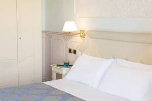 Schlafzimmer im Baia Imperiale Hotel mit weißen Möbeln und einem Bett.