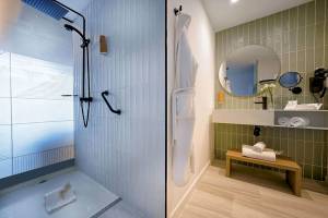 Badezimmer im H10 Costa Mogan Hotel mit Dusche, Handtuchhalter und grünen Fliesen.
