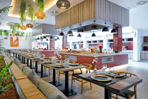 Innenbereich des H10 Costa Mogan Hotels mit Tisch, Stühlen und Speisenbuffet.