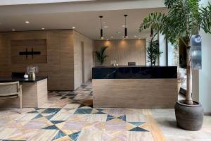 Empfangsbereich des H10 Costa Mogan Hotels mit Marmorboden, Holzmöbeln und Pflanzen.