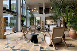 Lobby des H10 Costa Mogan Hotels mit moderner Einrichtung, geometrischem Bodendesign, großen Pflanzen und stilvollen Möbeln.