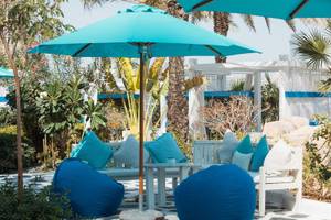 Lounge-Bereich des W Dubai - Mina Seyahi Hotels mit blauen Kissen, Sesseln und Sonnenschirmen.