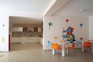 Innenansicht des Kinderzimmers im VOI Baia di Tindari Resort mit bunten Wandaufklebern und Möbeln.