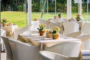 Restaurantterrasse im Acacia Palace Hotel mit weißen Tischen und Stühlen und Blick auf den Rasen